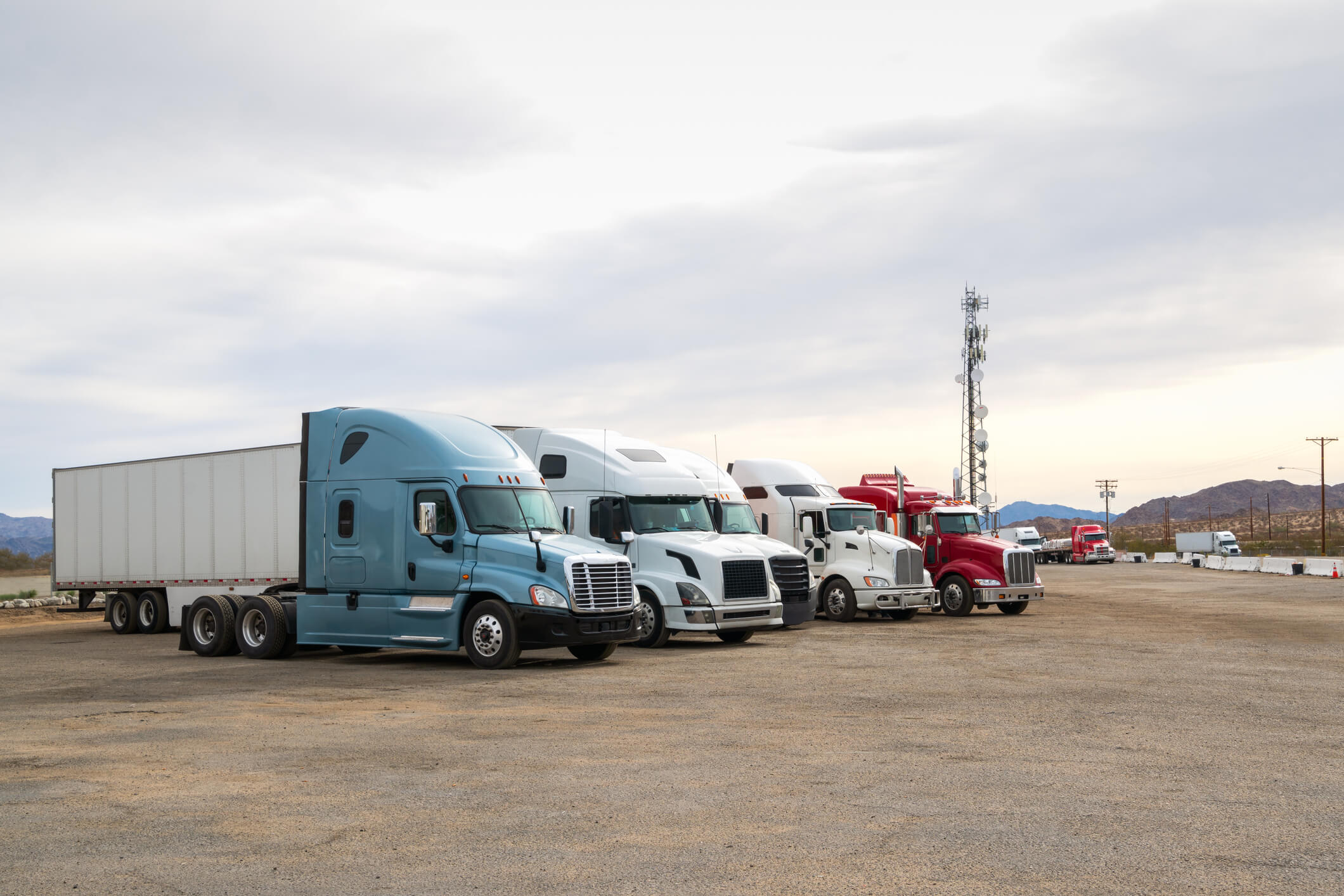 Five semi-trucks parked in a lot.