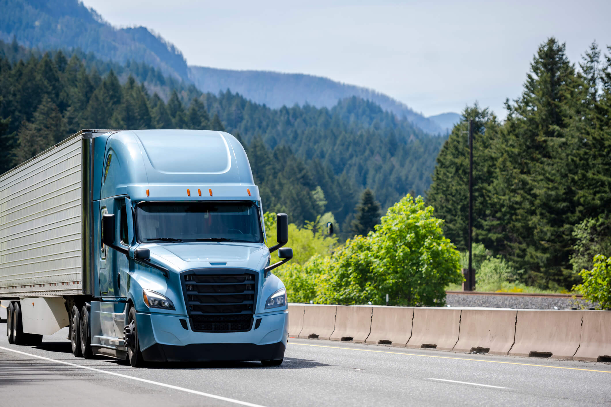 Light blue semi-truck driving on highway.