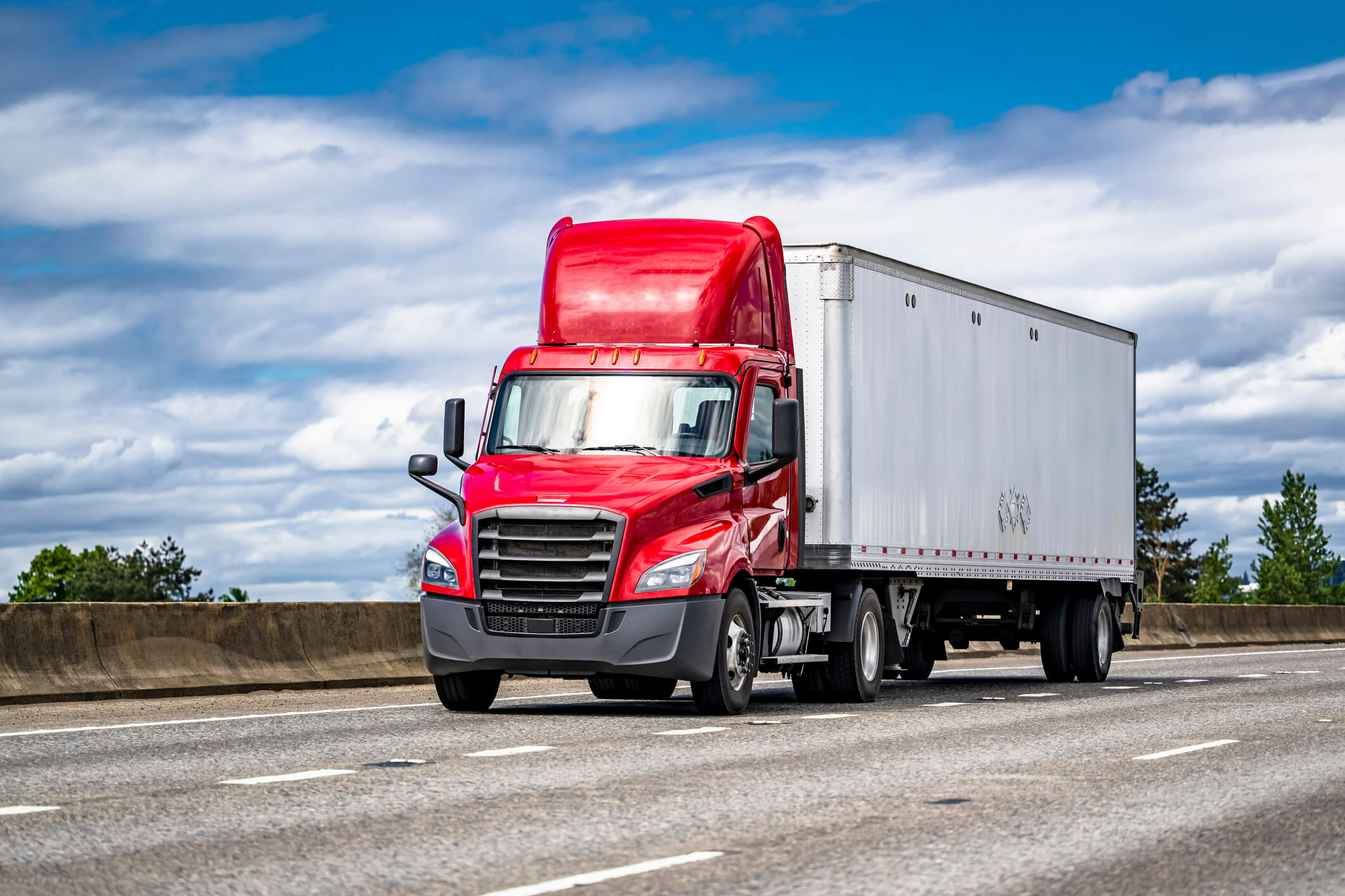 Red semi-truck driving on highway.