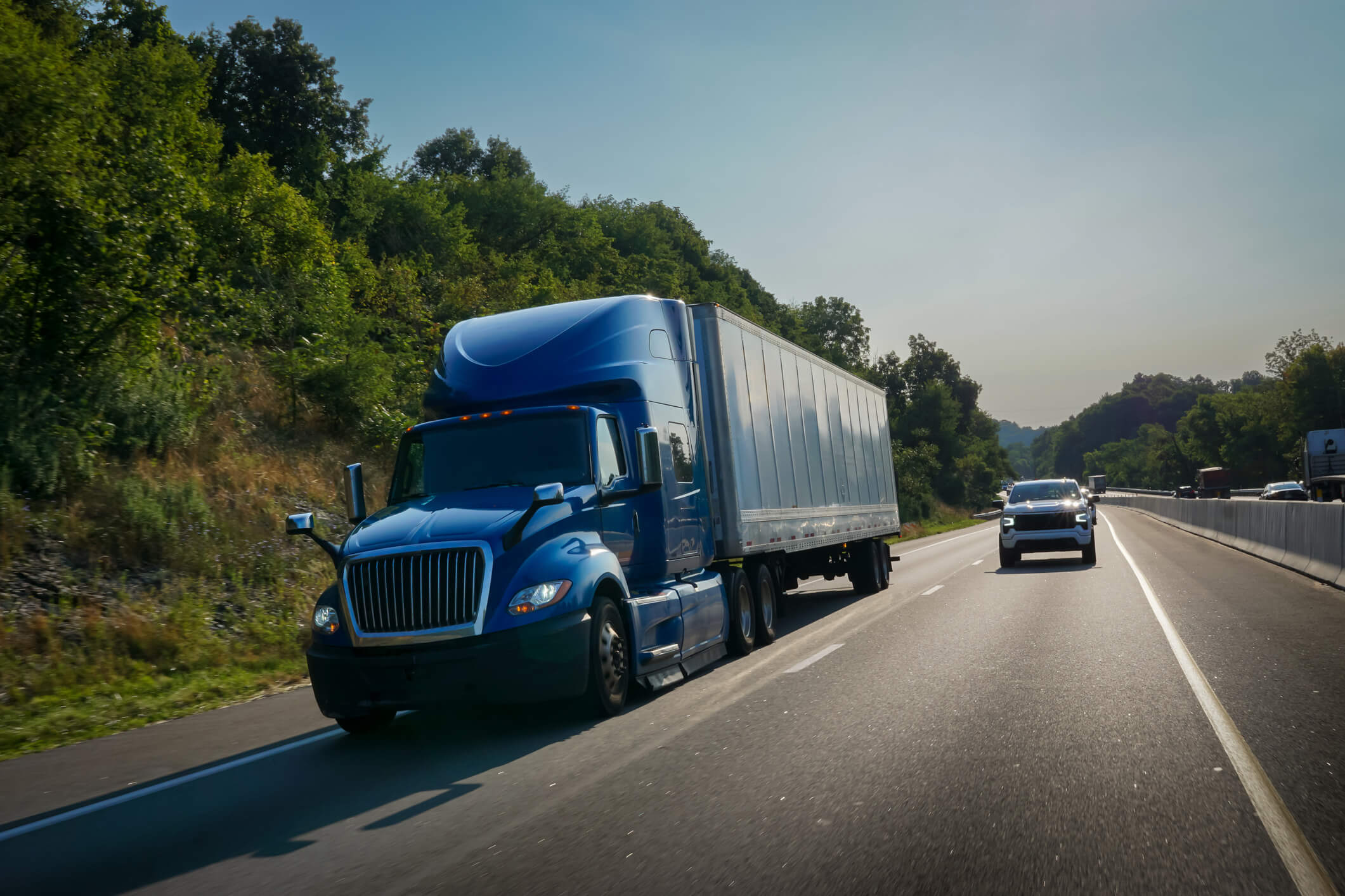 Blue semi-truck driving on highway.